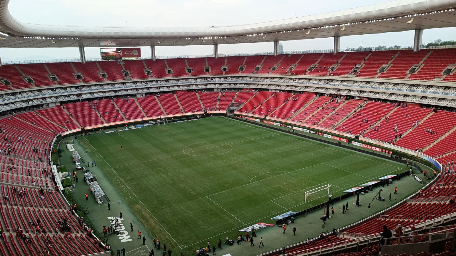 Interior del Estadio Akron: la cancha de futbol rodeada por los dos niveles de butacas rojas, el anillo blanco de palcos entre ellos y la cubierta.